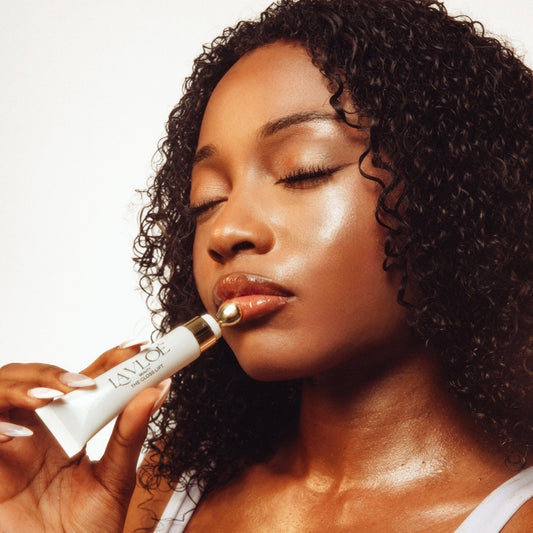 Woman applying lip balm with a close-up focus on her lips and the product.